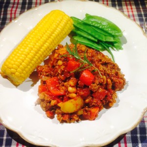 Chili Con Carne serverad på vit tallrik med en majskolv och gröna bönor